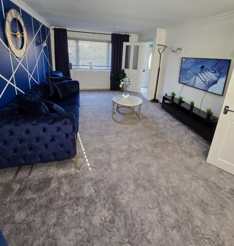 a living room with a blue couch and a table at Luxury Modern Comfy 3BR House Contractors Family in Kettering