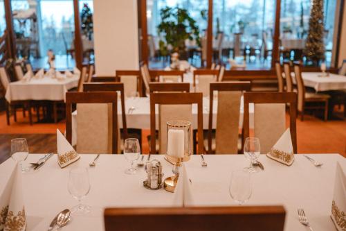 a dining room with white tables and chairs with wine glasses at Hotel Lesana in Vysoké Tatry