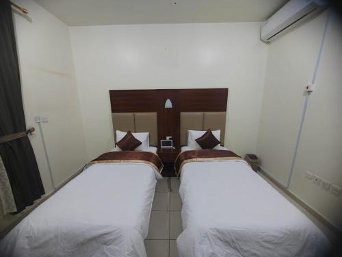 two beds in a room with white sheets at Al Eairy Apartments - Al Ahsa -2 in Al Ahsa