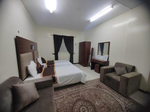 a bedroom with a bed and a couch and a chair at Al Eairy Apartments - Al Ahsa -2 in Al Ahsa