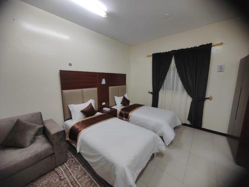 a hotel room with two beds and a couch at Al Eairy Apartments - Al Ahsa -2 in Al Ahsa