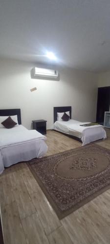 a bedroom with two beds and a rug on the floor at Al Eairy Apartment-Alqaseem 4 in Buraydah
