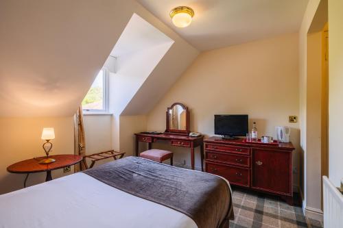 a bedroom with a bed and a tv and a mirror at Muthu Belstead Brook Hotel in Ipswich