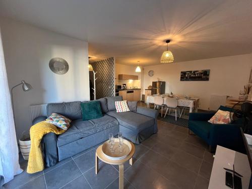 un salon avec un canapé bleu et une table dans l'établissement Charmant T3 à Arcachon avec terrasse et parking sécurisé - FR-1-374-233, à Arcachon