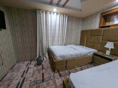 a bedroom with two beds and a window at The Jade Palace, Hunza in Karimabad Hunza