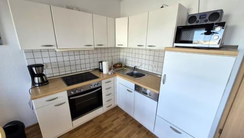 a small kitchen with white cabinets and a white refrigerator at FLOATING HOUSES Classic _ _Schwimm in Barth