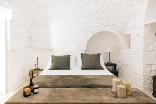 a bedroom with a bed in a white brick wall at Trullo dei Cinque in Cisternino