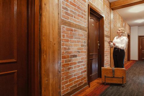 a woman standing in front of a brick wall at Hotel Młyn Aqua Spa in Elblag
