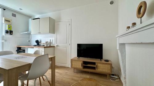 un salon avec une télévision et une table avec des chaises dans l'établissement Le bel air, à Pougues-les-Eaux