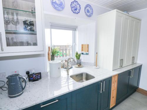 a kitchen with blue and white cabinets and a sink at Nead na bhFáinleog Swallows Nest in Aughrus More