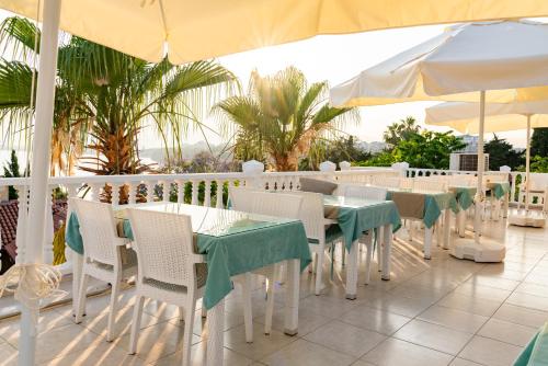 a restaurant with white tables and chairs and umbrellas at Bacchus Pension in Antalya