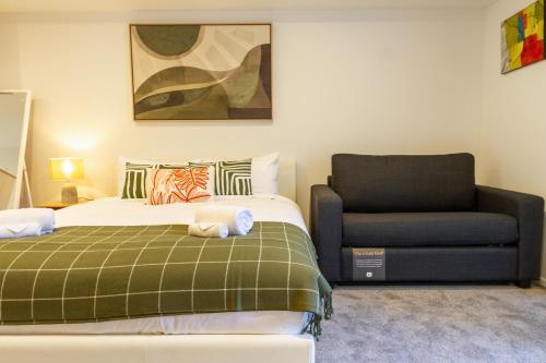 a bedroom with a bed and a chair at Bright & New Studio Unit Walk to Town in Christchurch