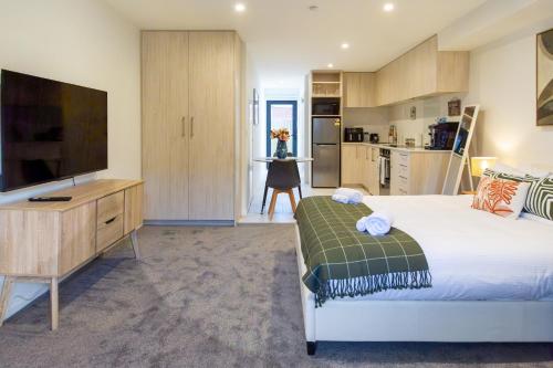 a bedroom with a large bed and a television at Bright & New Studio Unit Walk to Town in Christchurch