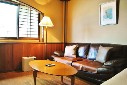 a living room with a leather couch and a table at Hotel Kazahaya in Hita