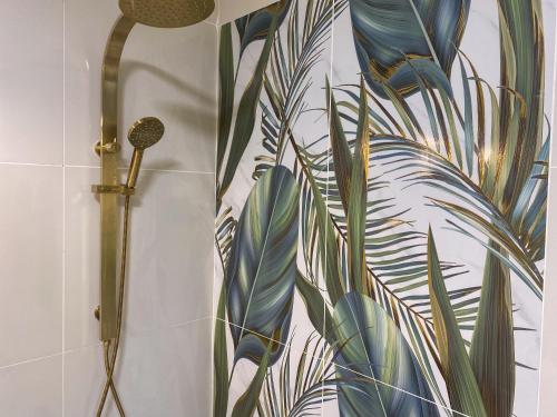 a bathroom with a shower with a mural of a plant at Korora Hideaway in Coffs Harbour