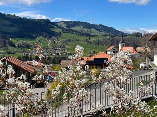 a town in the mountains with flowering trees at Au Chant des Grillons - studio ensoleillé en Gruyère in Estavannens-Dessous