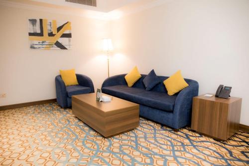 a living room with two blue couches and a coffee table at فندق اهلا Hola Hotel in Al Jubail