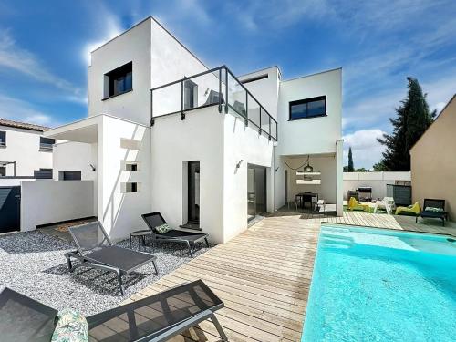 une maison blanche avec une piscine devant dans l'établissement villa PIVOINES, à Sérignan