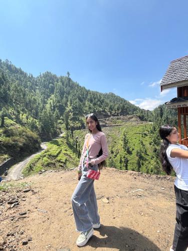 two women standing on top of a mountain at Apple Land by Naavagat in Jibhi
