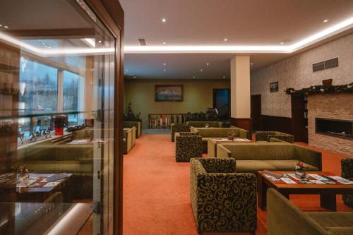 a restaurant with couches and tables and a fireplace at Hotel Lesana in Vysoké Tatry