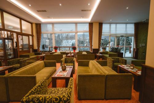 a living room with couches and tables and windows at Hotel Lesana in Vysoké Tatry