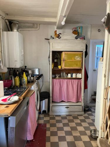 une cuisine avec un vieux réfrigérateur avec un rideau rose dans l'établissement Maison de pêcheur petite vue mer centre village, à Villerville