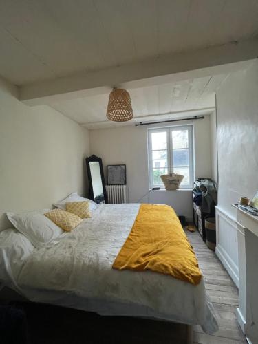 une chambre avec un grand lit avec une couverture jaune dans l'établissement Maison de pêcheur petite vue mer centre village, à Villerville
