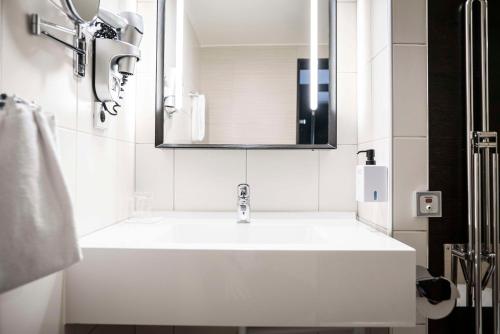 a white bathroom with a sink and a mirror at Scandic Anglais in Stockholm