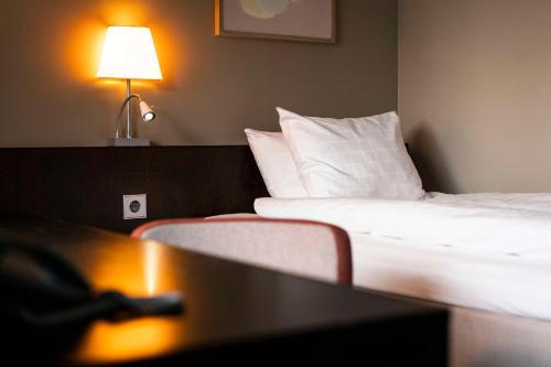 a hotel room with a bed and a table with a lamp at Scandic Anglais in Stockholm