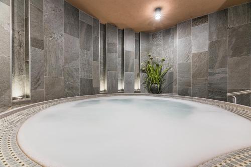 a large white tub in a bathroom with tiles at Hotel Lesana in Vysoké Tatry