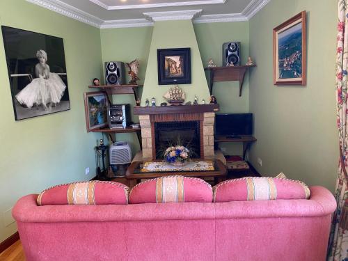 ein rosafarbenes Sofa im Wohnzimmer mit Kamin in der Unterkunft Villa Pepita in Ayuela