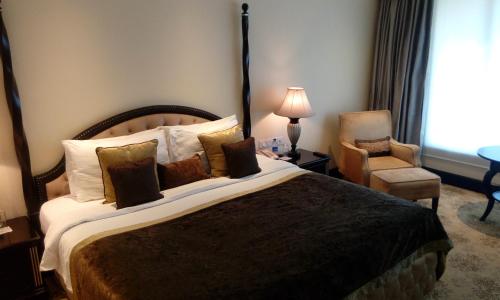 a hotel room with a large bed and a chair at Taj Krishna in Hyderabad
