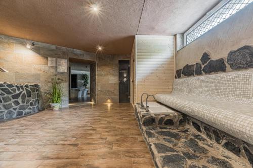 a large room with a stone wall with a bench at Hotel Lesana in Vysoké Tatry