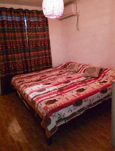 a bed in a bedroom with a red comforter at Chaleureuse maison située a 1 minute de la plage in Le Morne