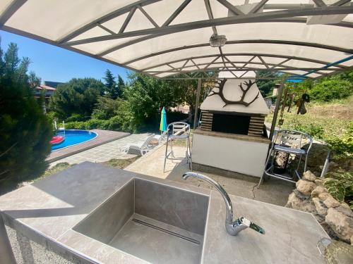 a kitchen sink under an umbrella next to a pool at Villa Stella - private house with parking spot, pool and sea view in Varna City