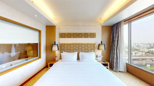 a bedroom with a large bed and a large window at Radisson Blu Hotel, Nagpur in Nagpur