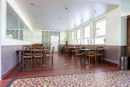 une salle à manger avec des tables et des chaises en bois dans l'établissement Gite Le Relais Saint Michel, à Domfront