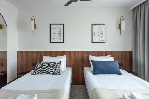 two beds in a room with white and blue pillows at AIRINN Vilnius Airport Hotel RENOVATED 2025 in Vilnius