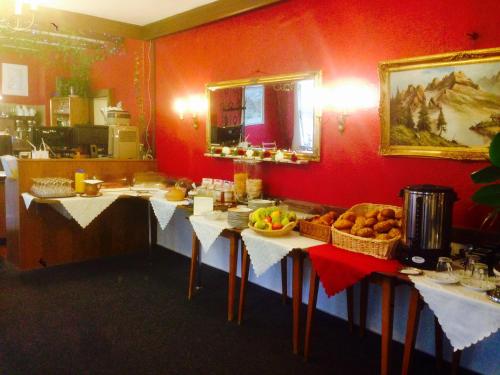 a kitchen with red walls and tables with baskets of food at Pension Dören in Bruttig-Fankel