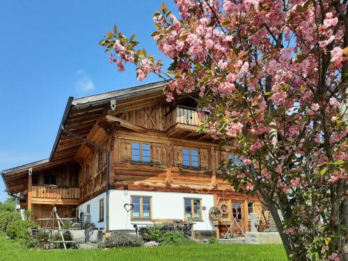 a log cabin with a flowering tree in front of it at Ferienwohnung Allgäutraum mit Bergblick in Oy-Mittelberg