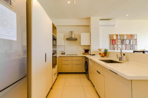 a kitchen with white counters and a sink at Cap Ouest by Horizon Holidays in Flic-en-Flac