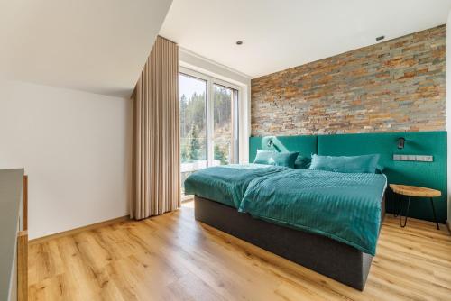 Un dormitorio con una cama verde y una pared de ladrillo en DearDeer apartmán s terasou, en Železná Ruda