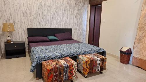 a bedroom with a bed with two ottomans in front of it at Hill View Park Guest House Citihousing jhelum satellite town in Jhelum