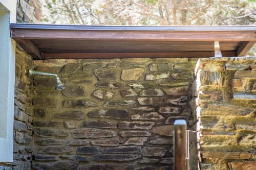 a building with a stone wall with a shower at Casa Vacanze Sabina - Stintino in Stintino