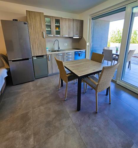 a kitchen with a table and chairs and a refrigerator at Apartman Sol Nin in Nin
