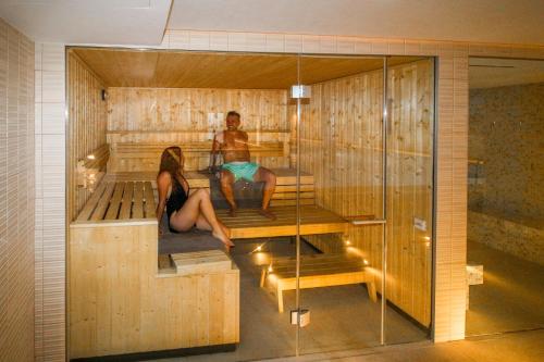 a man and a woman sitting in a sauna at Aparthotel Duva & Spa in Port de Pollensa