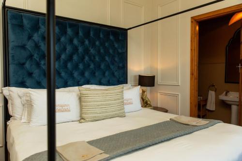 a bed with a blue headboard and white pillows at Sonnekus Boutique Hotel & Bistro in Kalk Bay