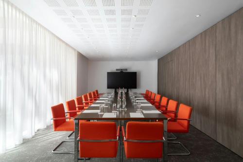 a conference room with a long table and orange chairs at JW Marriott Cannes in Cannes