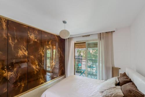 une chambre avec un lit et une grande fenêtre dans l'établissement Central T2 Cannes Suquet - terrasse - WIFI - Clim, à Cannes