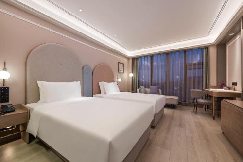 a hotel room with two beds and a desk at Mercure Nantong Suxitong Riverside in Nantong